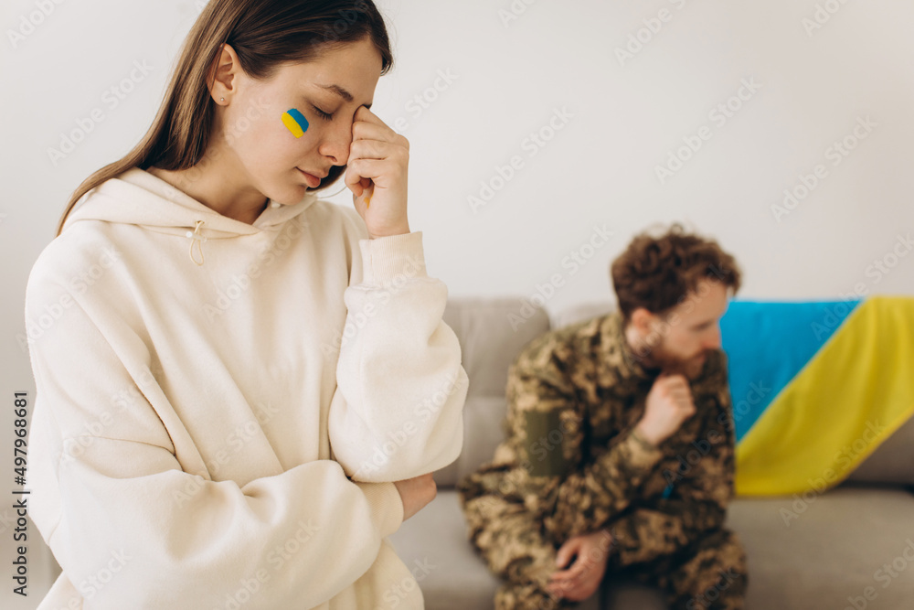 A Ukrainian woman mourns and says goodbye to her military husband in a uniform holding a Ukrainian flag at home A Ukrainian woman mourns and says goodbye to her military husband in a uniform holding a Ukrainian flag at home