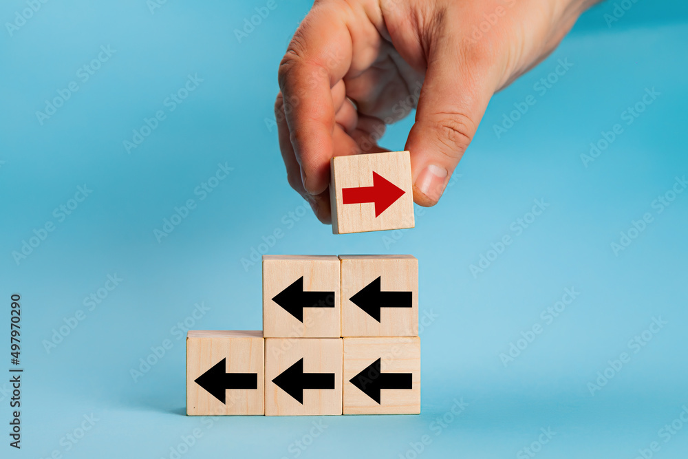 businessman-hand-picked-wooden-block-with-red-arrow-facing-the-opposite
