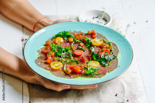 Tuna carpaccio with vierge sauce. Served with cherry tomatoes and arugula. Fresh Italian appetizer. Italian mediterranean cuisine with seafood