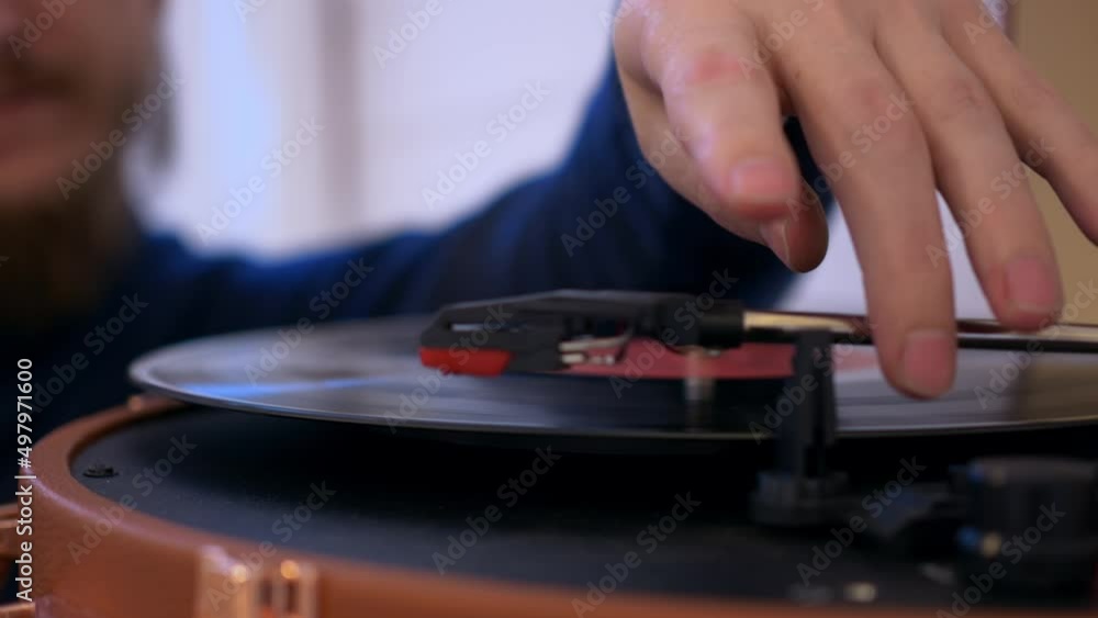 Closeup of a man putting a vinyl record into a turntable, the record