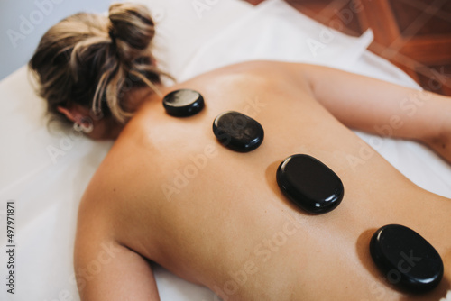 Hot spa volcanic lava stone placed on a female patient's back, by a physiotherapist. Energy stones.
