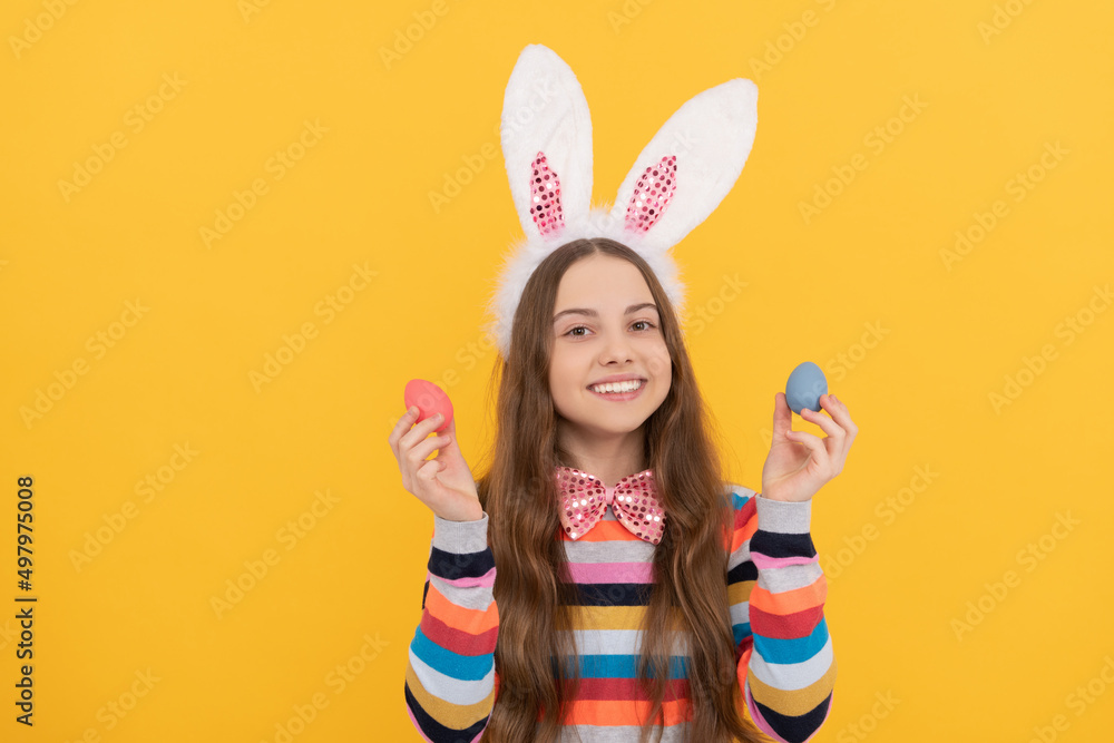 smiling teen child in bunny ears and bow tie hold easter eggs on yellow background smiling teen child in bunny ears and bow tie hold easter eggs on yellow background