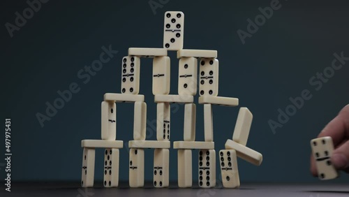 Falling dominoes. Chain reaction, built figure of dominoes falling in slow motion. Domino house.