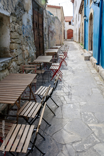 Empty narrow pedestrian street with cafe tables and chairs in Limassol Old town, Cyprus © Olga