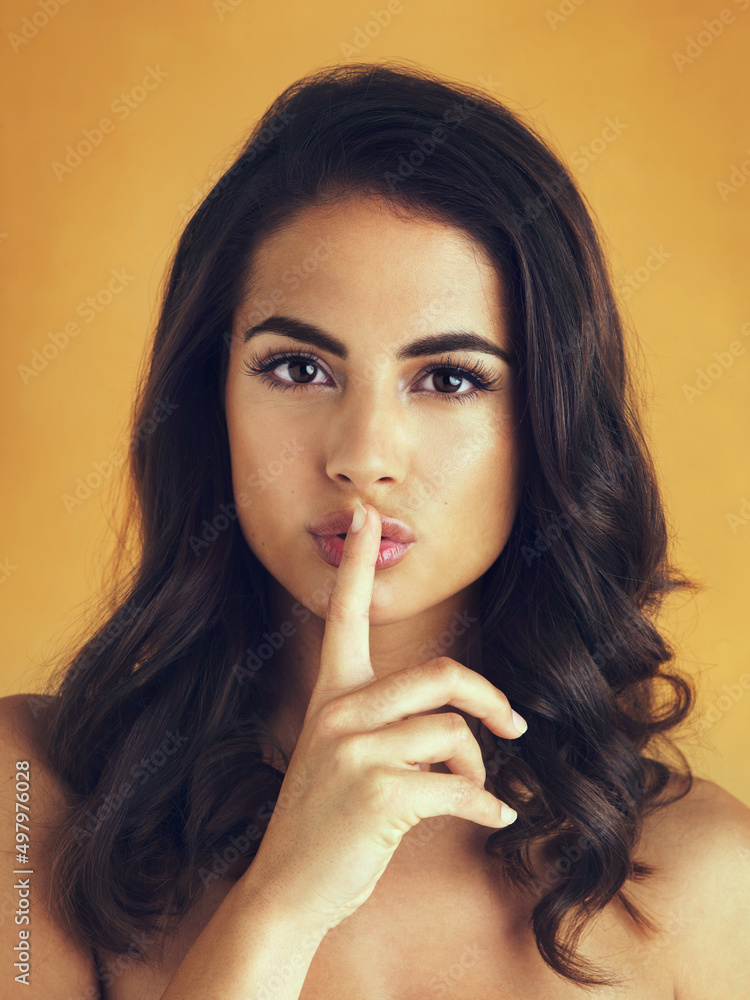 Words cant describe her beauty. Shot of a beautiful woman posing with her finger on her lips against a yellow background. Words cant describe her beauty. Shot of a beautiful woman posing with her finger on her lips against a yellow background.