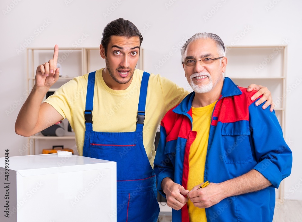 Two contractors repairing fridge at workshop Two contractors repairing fridge at workshop