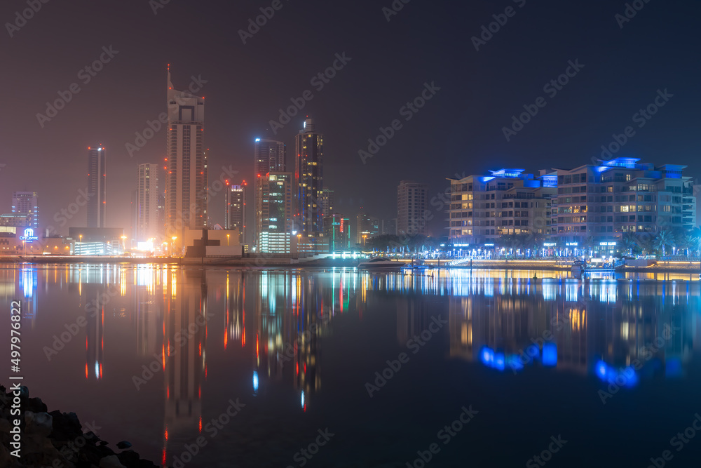 Manama, Bahrain city skyline at night reflecting off the water