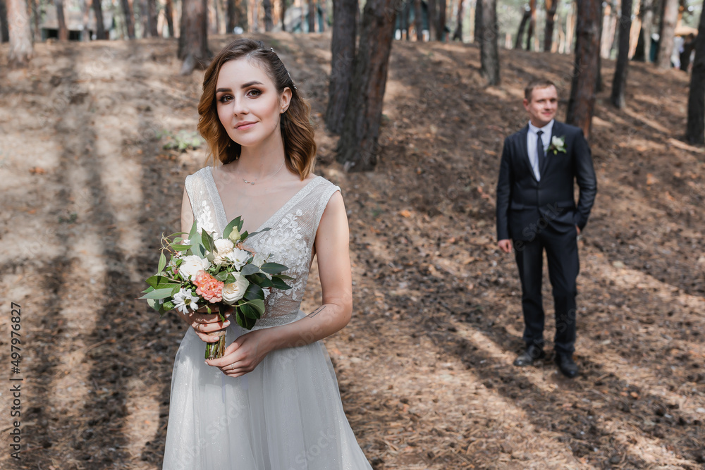Fototapeta premium Wedding couple in the park. An elegant bride of European appearance and a groom in a black suit.