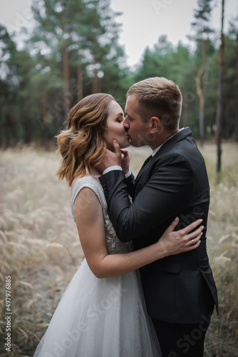 Wedding couple in the park. An elegant bride of European appearance and a groom in a black suit.