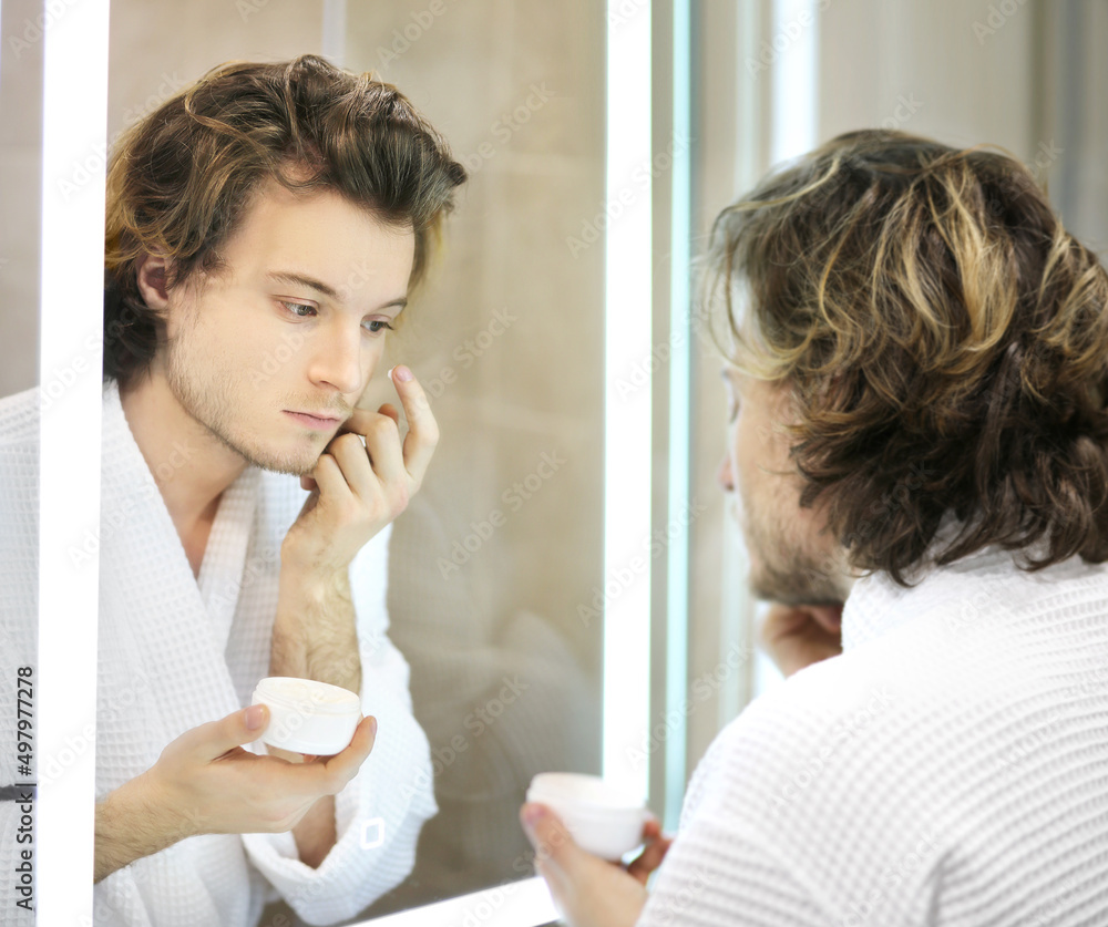 young man looking in the mirror,combing his hair,looking at problems on face. young man looking in the mirror,combing his hair,looking at problems on face.