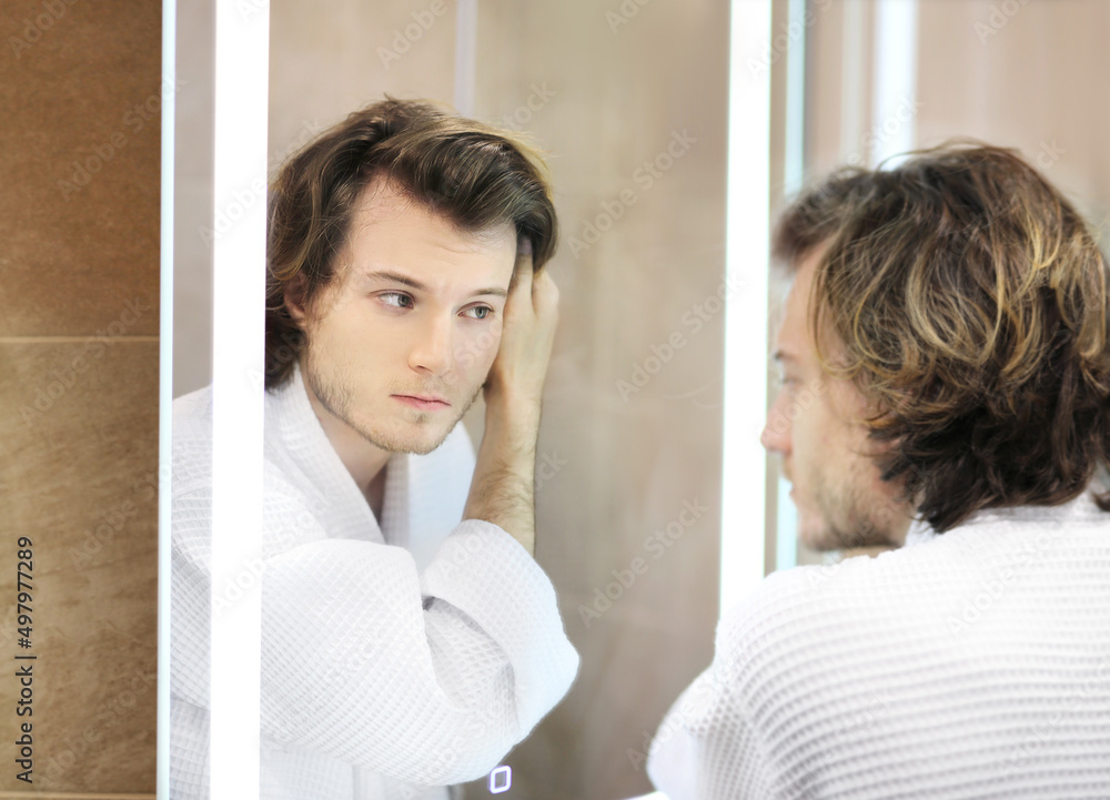 young man looking in the mirror,combing his hair,looking at problems on face. young man looking in the mirror,combing his hair,looking at problems on face.