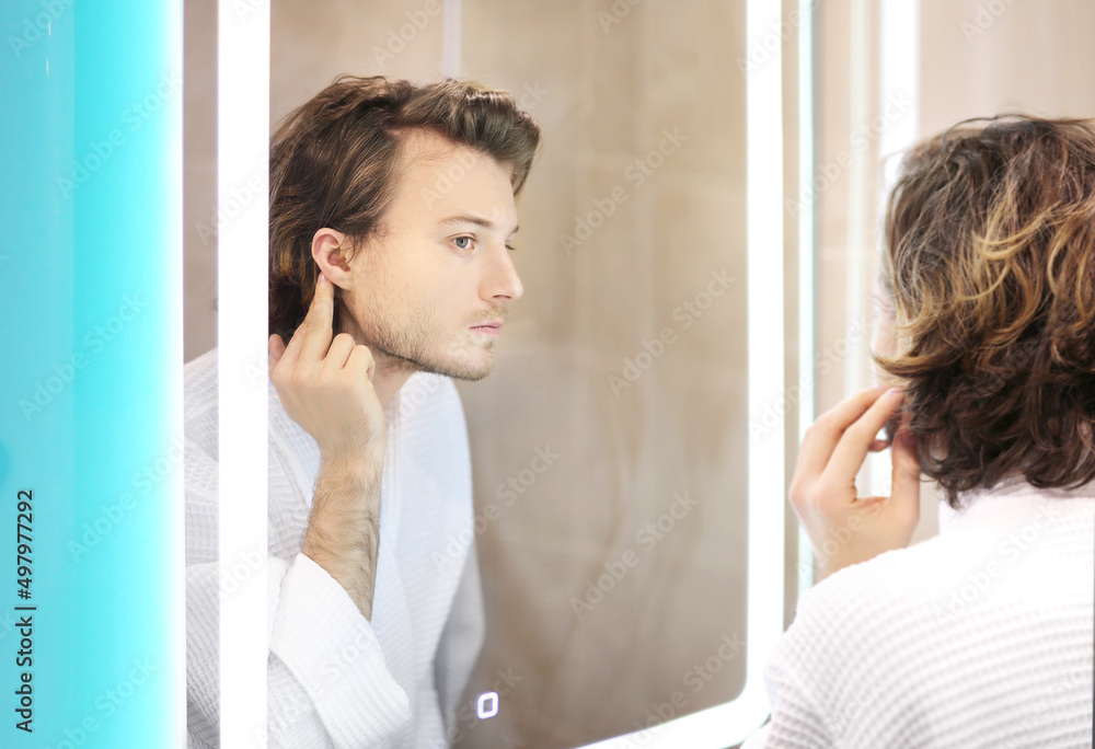 young man looking in the mirror,combing his hair,looking at problems on face. young man looking in the mirror,combing his hair,looking at problems on face.