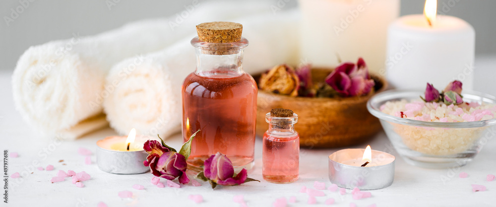 Concept of spa treatment in salon. Natural organic oil, towel, candles as decor. Atmosphere of relax, serenity and pleasure. Anti-stress and detox procedure. Luxury lifestyle. White background, banner