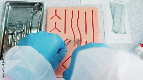 Surgeon trains to apply stitches on a special silicon pad, medical attributes photo