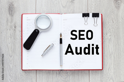 SEO AUDIT. Business concept. text on an open notepad. there is a magnifying glass on the notebook