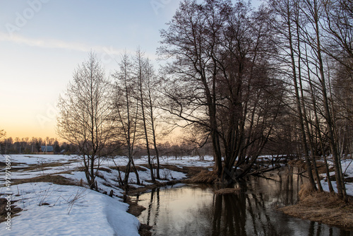 Melting ice and snow. Spring landscape, evening forest with a river. The beginning of spring. Awakening of nature. Charming landscapes of spring nature.