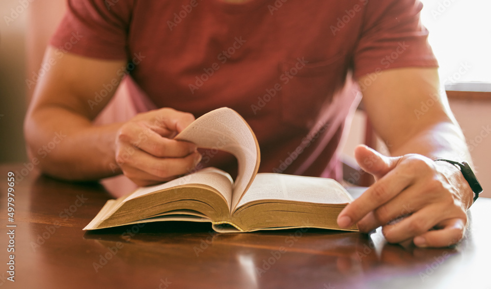 Praying is important for peace of mind. Shot of a young man sitting at a table reading his bible. Praying is important for peace of mind. Shot of a young man sitting at a table reading his bible.