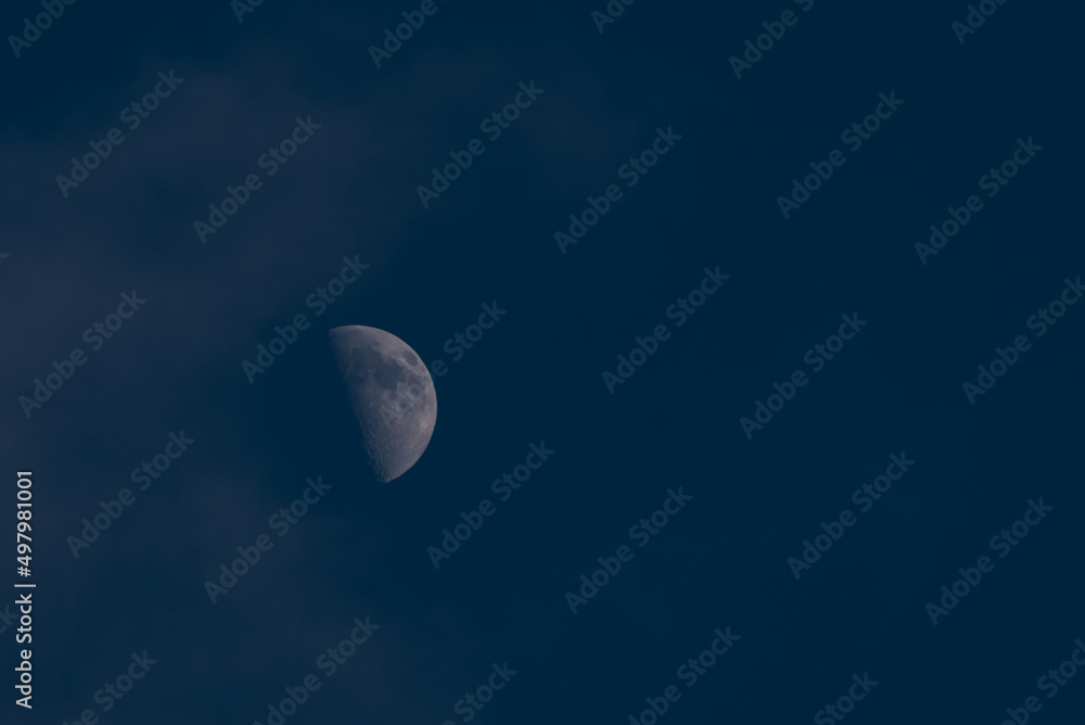 A close-up moon with visible craters against a dark blue sky. A close-up moon with visible craters against a dark blue sky.