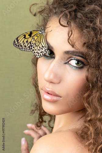 Fashion beauty model with butterfly on face and color professional makeup. SPA, wellness, make-up and skincare concept.