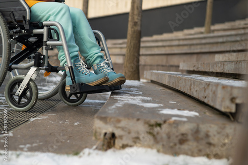 Woman in a wheelchair near the stairs in the park in winter.