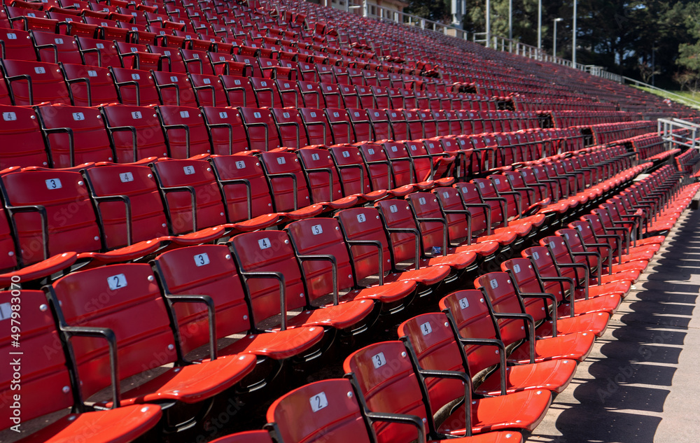 Naklejka premium Many rows of red and black numbered seats in an outdoor stadium