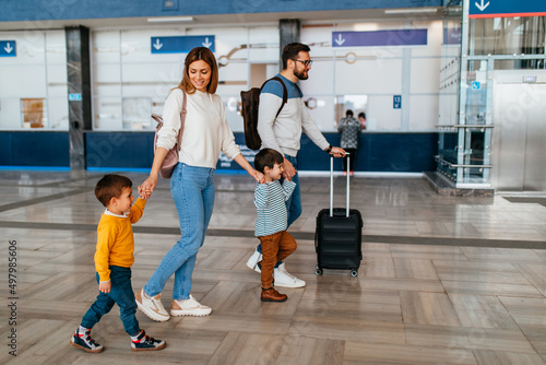Fotografie Happy ypung family with luggage in railroad station go together on vacation