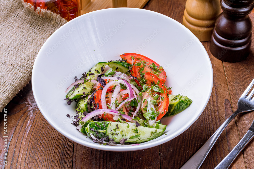 Vegetable salad with tomatoes and cucumbers and red onion on wooden table Vegetable salad with tomatoes and cucumbers and red onion on wooden table