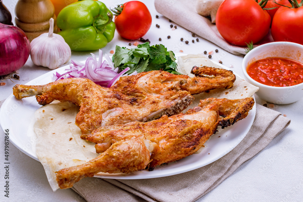 fried chicken tobacco with tomato sauce and red onion on white plate fried chicken tobacco with tomato sauce and red onion on white plate