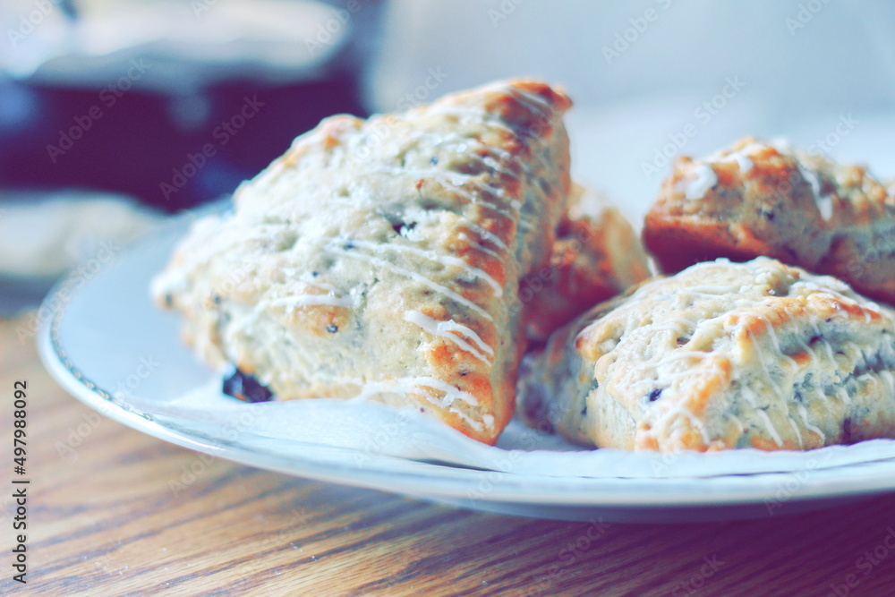 blueberry scones served in a white plate on a wooden table, pictured in modern tones.