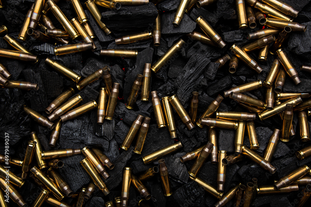 Empty shells from weapons on black smoldering coals. Consequences of the war. Dark back. Empty shells from weapons on black smoldering coals. Consequences of the war. Dark back.