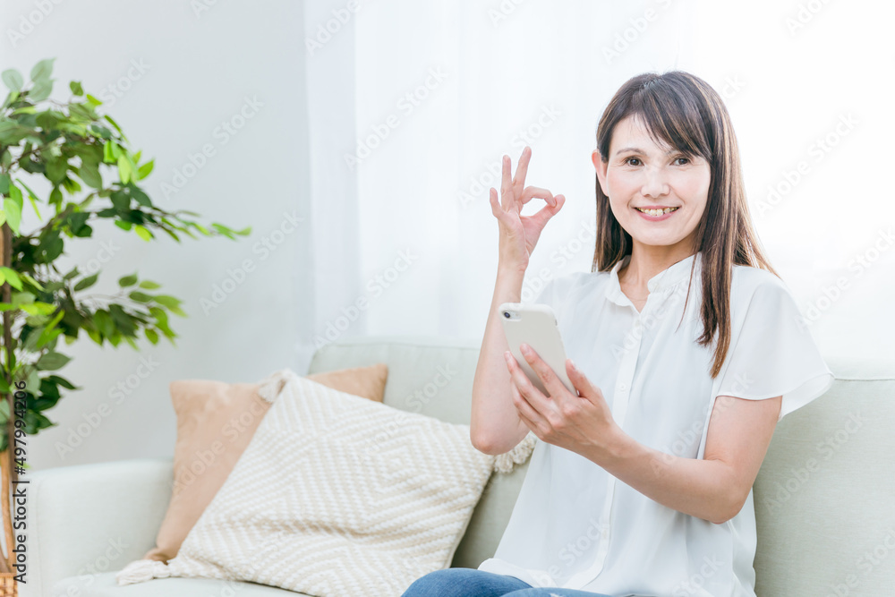 ソファに座る中高年女性（見る）
