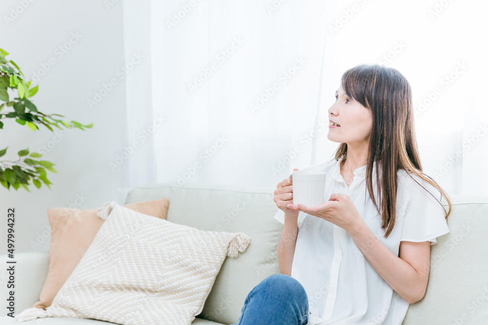 ソファに座る中高年女性(飲み物)
ソファに座る中高年女性(飲み物)