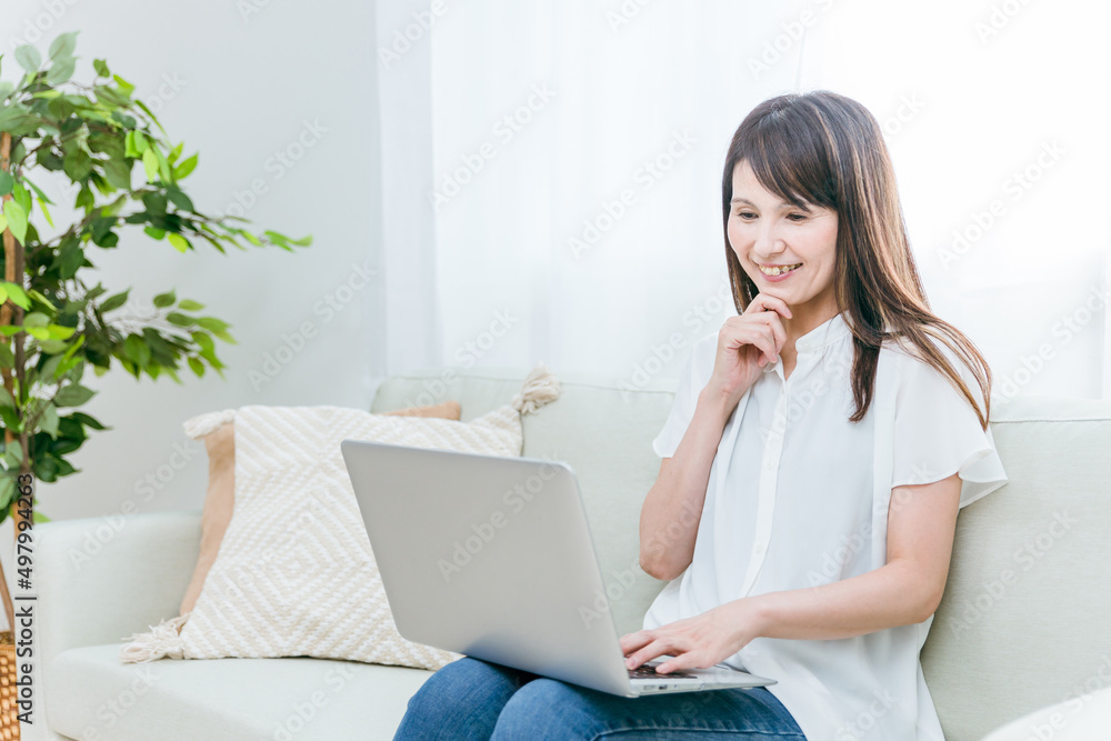 ソファに座る中高年女性(パソコン)
ソファに座る中高年女性(パソコン)