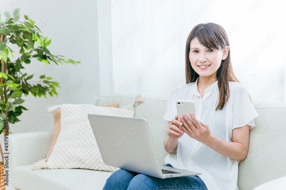 パソコンとスマホを使うミドル世代の女性
