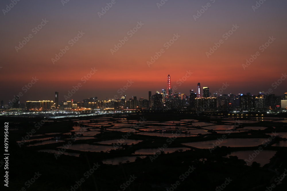 Shenzhen skyline , with skyscrapers and office against fish farm or fish ponds, during dramatic moment in evening, from the view of boundary of Hong Kong suburb where is named Ma Tao Lung