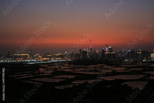 Shenzhen skyline   with skyscrapers and office against fish farm or fish ponds  during dramatic moment in evening  from the view of boundary of Hong Kong suburb where is named Ma Tao Lung