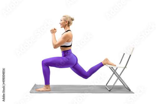 Workout with props. Attractive caucasian woman in purple leggings does lunges using a chair, isolated on white.