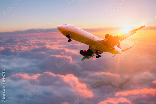 Passenger airplane. Passengers commercial airplane flying above clouds in sunset light. Business trip. Commercial plane. Concept of fast travel, holidays and business.