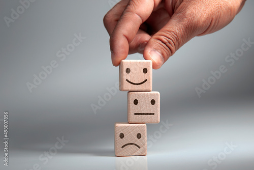 Hand of a businessman chooses a smiley face on wood block cube, The best excellent business services rating customer experience, Satisfaction survey concept