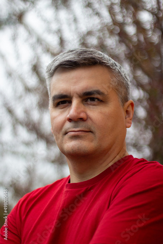Portrait of a man 40-50 years old, gray-haired, swarthy. Serious look. Big eyebrows. Red jersey. Looking into the distance