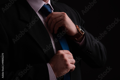 man with hand on tie in suit with watch on wrist photo