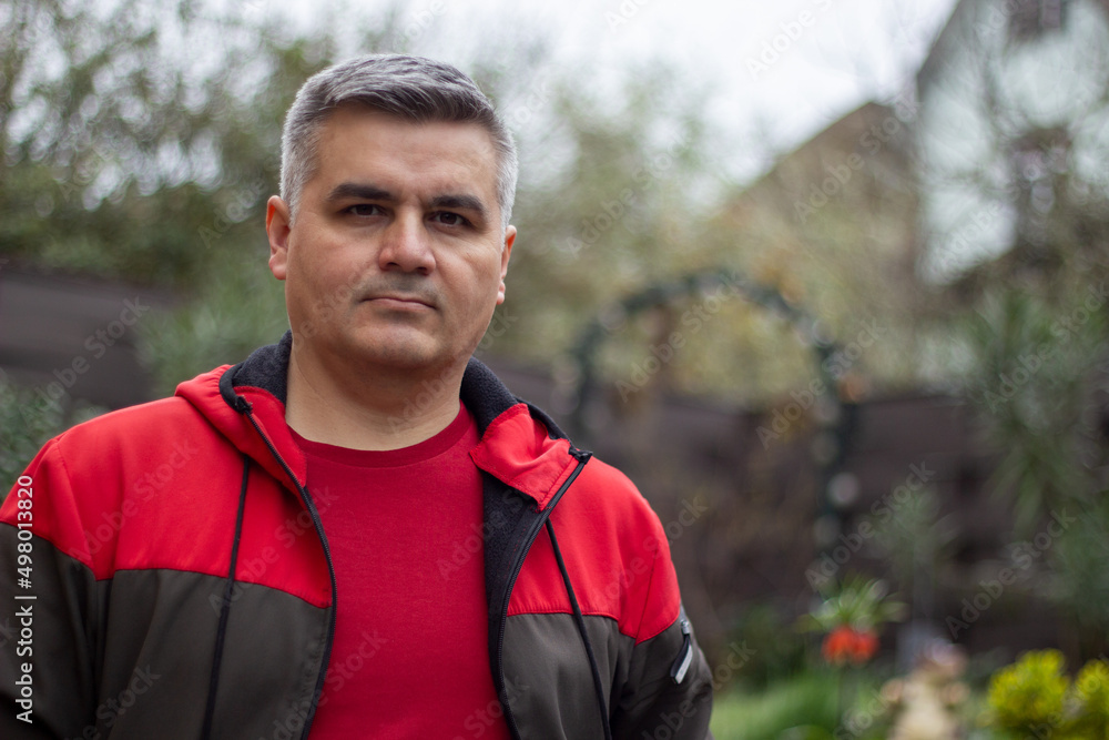 Portrait of a man 40-50 years old, gray-haired, swarthy. Serious look. Big eyebrows. Red jacket. Looking at the camera Portrait of a man 40-50 years old, gray-haired, swarthy. Serious look. Big eyebrows. Red jacket. Looking at the camera