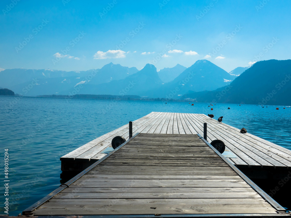 Panoramic view of an austrian lake with wooden pier and mountain range in the background. Salzkammergut, Upper Austria