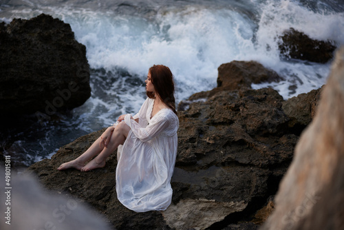 Fototapeta Naklejka Na Ścianę i Meble -  barefoot woman in white dress sits on a cliff nature top view