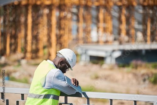 Head and shoulders portrait of bearded construction foreman speaking by walkie-talkie giving instructions to workers on site