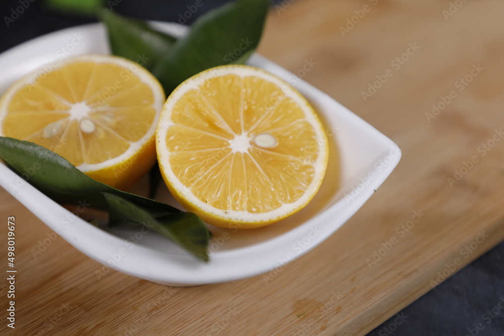 Fresh sliced lemon on plate with green leaves. Fresh sliced lemon on plate with green leaves.