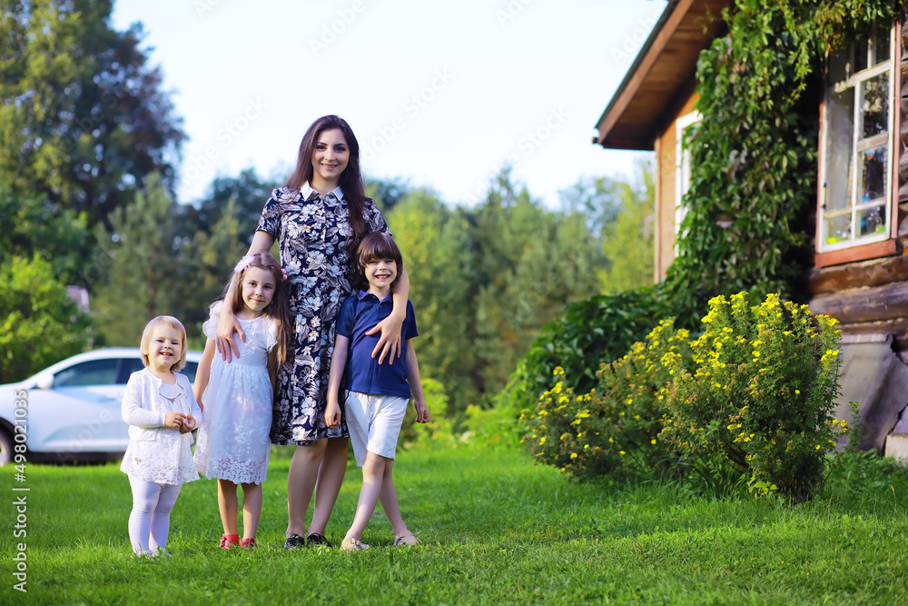 Young large family on a summer morning walk. Beautiful mother with children is playing in the park.