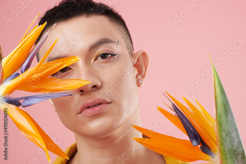 Face of young man wearing bright colorful rhinestones eye makeup photo