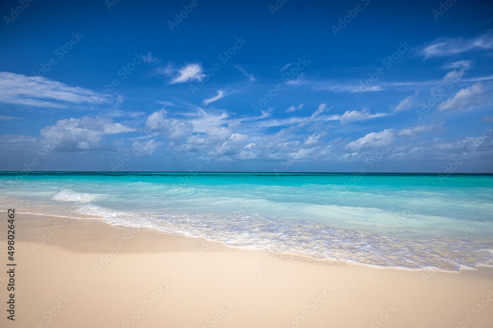 Closeup sandy beach waves and blue summer sky. Panoramic beach landscape. Empty tropical beach and seascape, horizon. Bright blue sky, soft sand, calmness, tranquil seaside relaxing sunlight, summer 