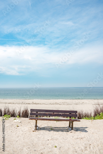 Cover page with a lonely bench at beach of Dune island near Helgoland at Northern Sea for birds and nature watching, Germany, summer.